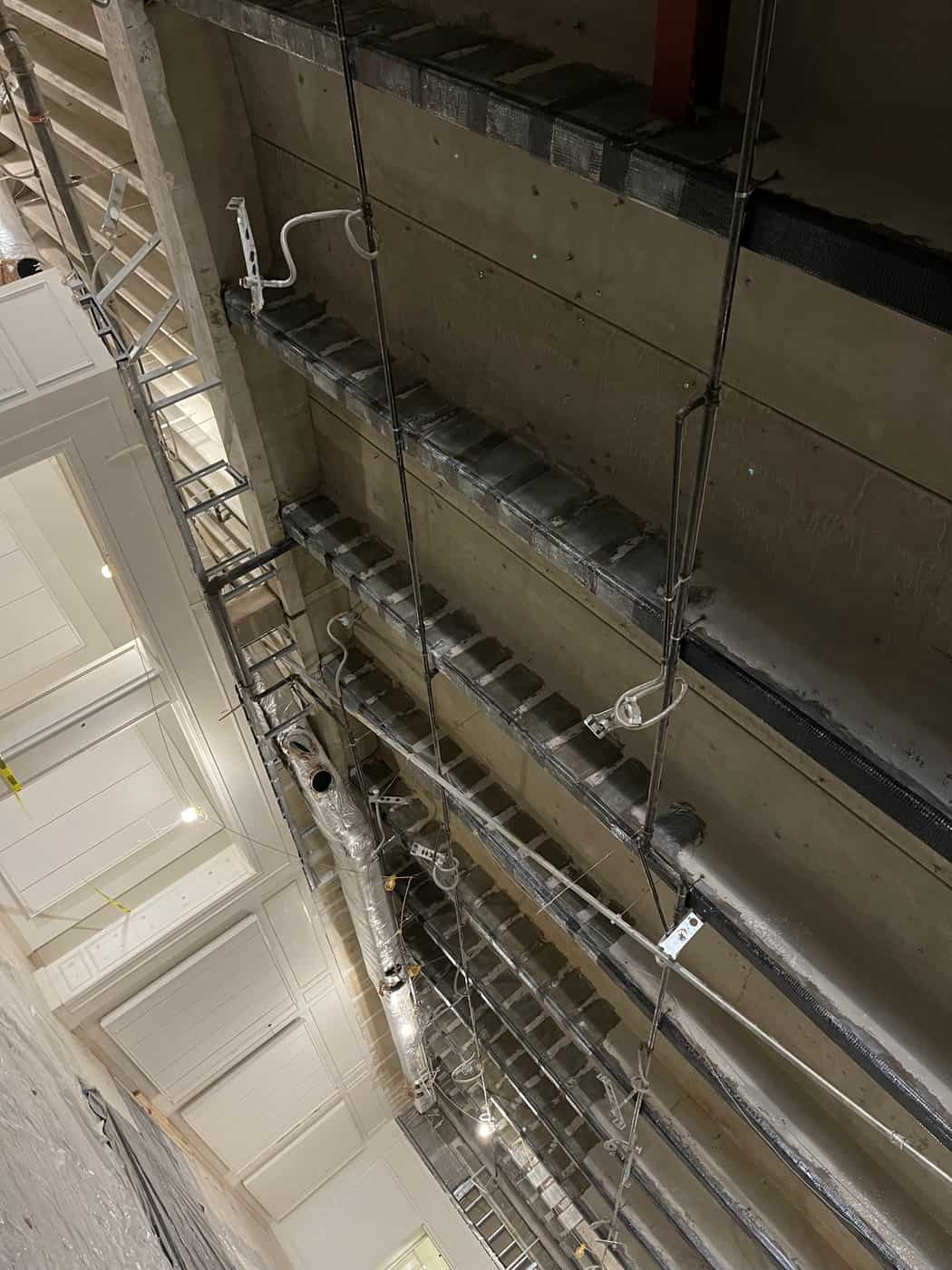 Joist soffits with carbon fiber strips beside a wall.