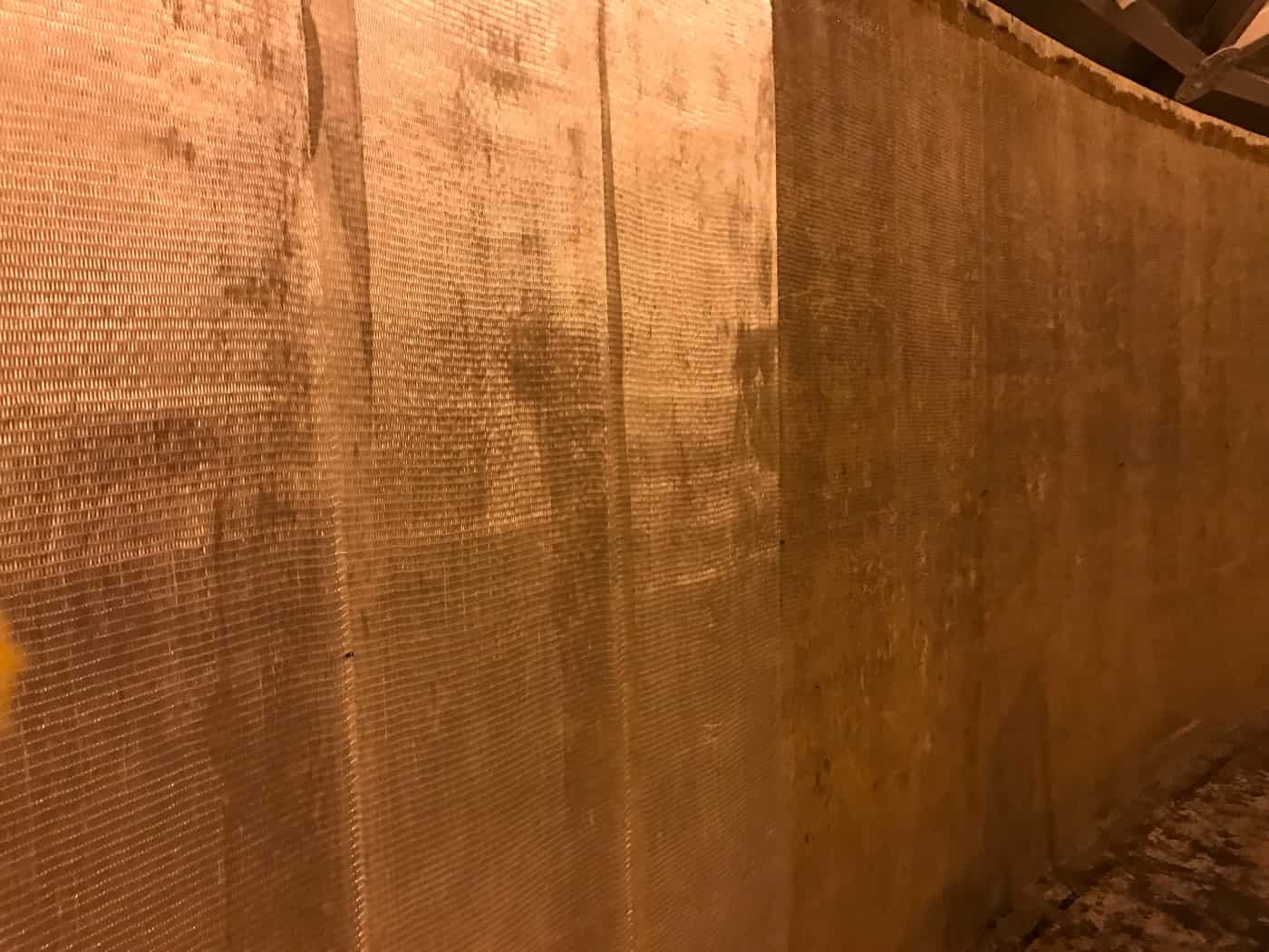 Interior concrete wall covered with saturated glass fiber fabric showing its weave.