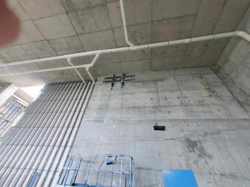 Tall concrete wall with hash-pattern composite strips around a penetration, lift below.