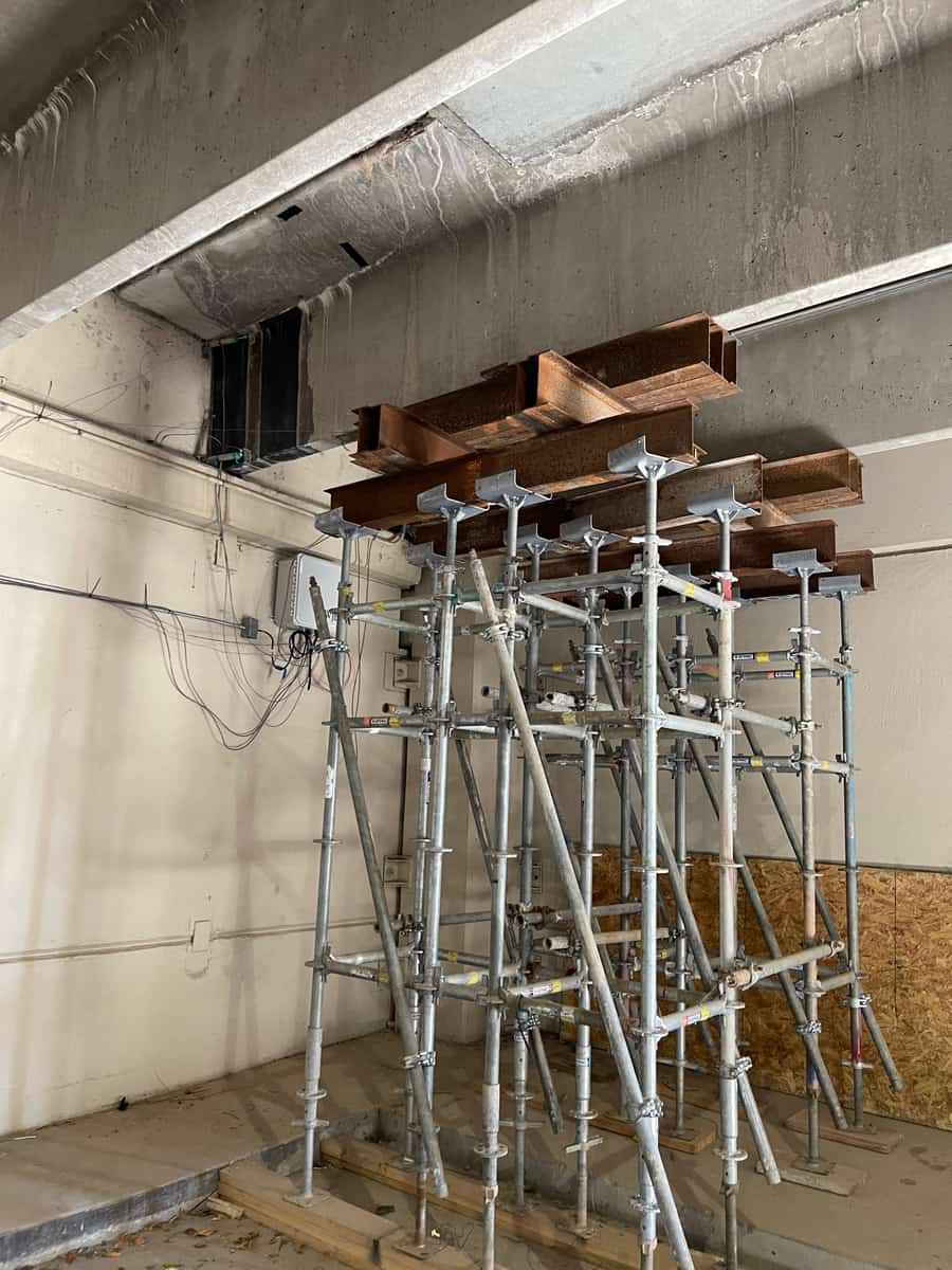 Shoring towers with timber cribbing under a concrete beam.