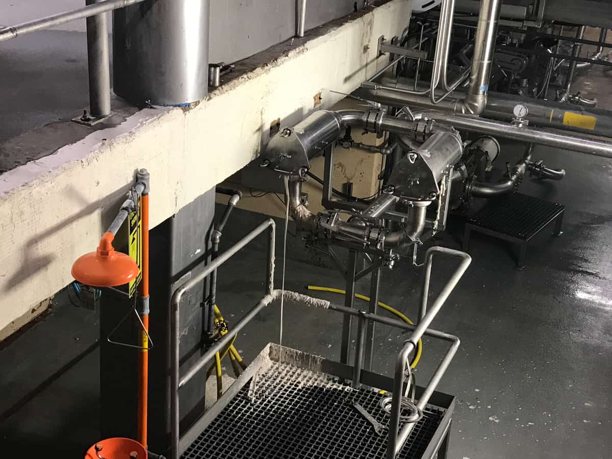Raised concrete platform edge with an eyewash station and stainless equipment.