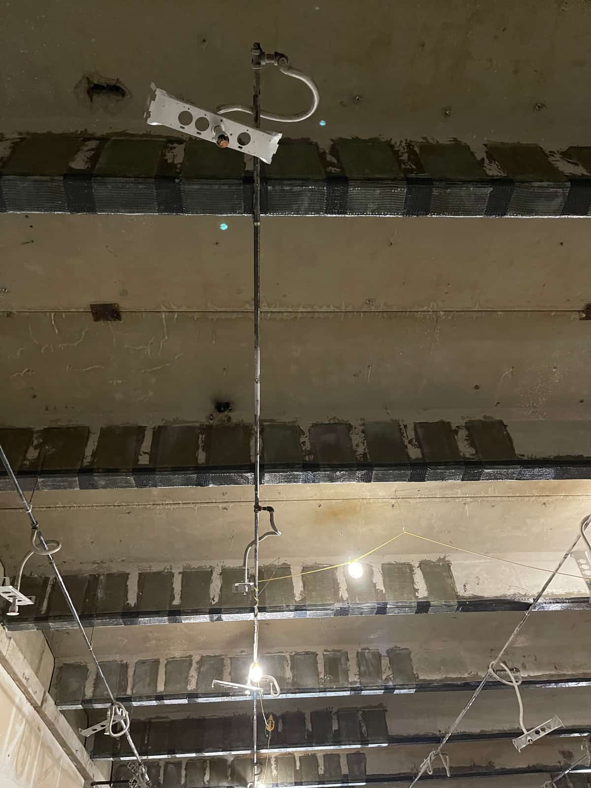 Close view of carbon fiber U-wraps on concrete joists along a girder line.