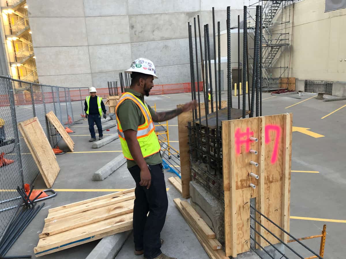 Worker beside a column form with rebar on a rooftop deck.