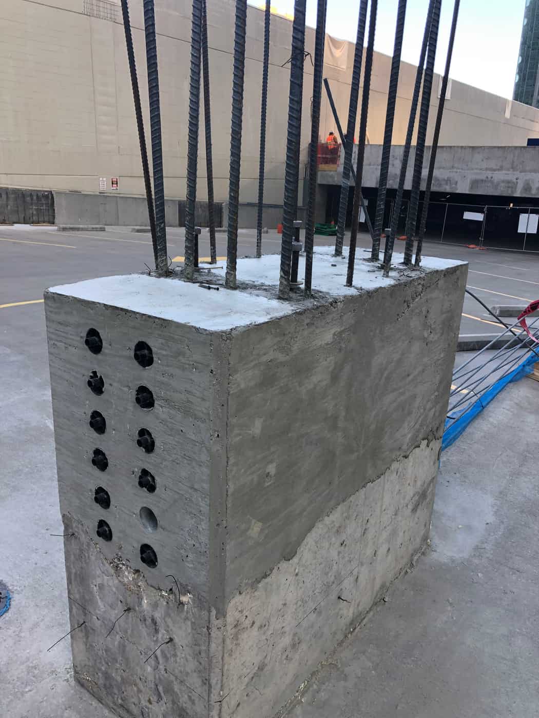 New concrete column extension with rebar and sleeve holes on a rooftop deck.