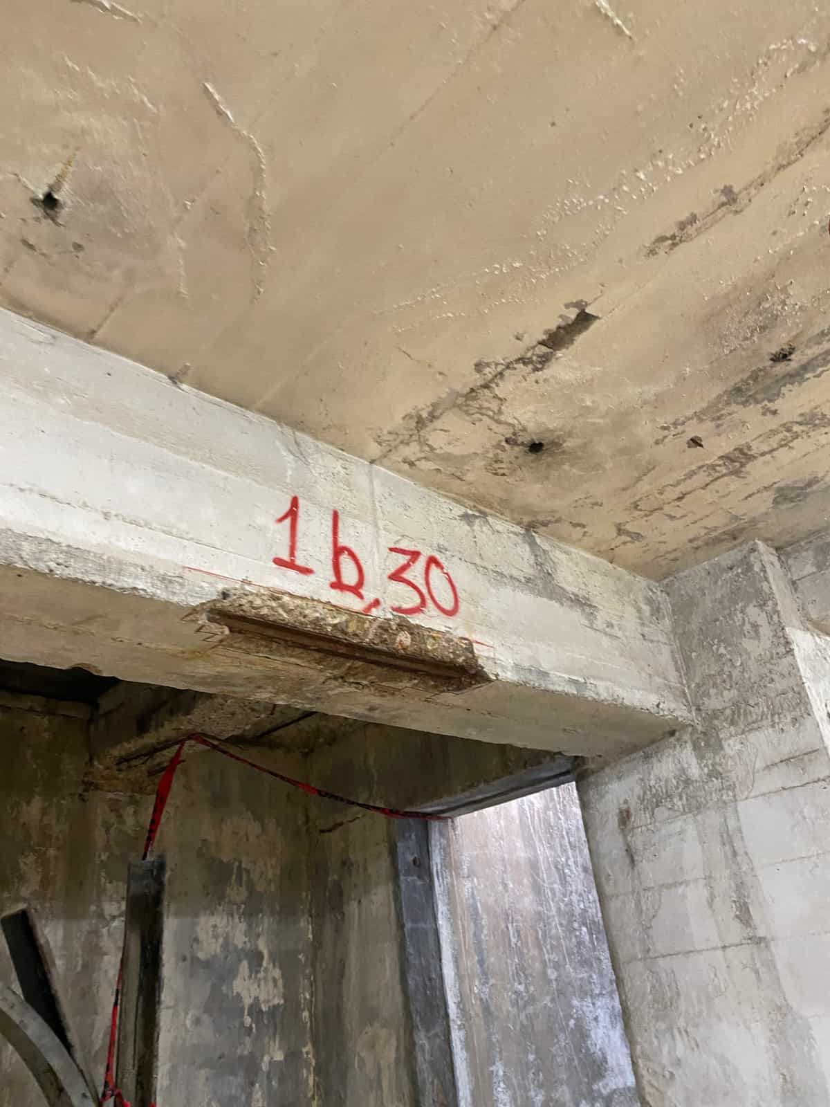 Concrete beam soffit over a doorway with a spalled, patched area.