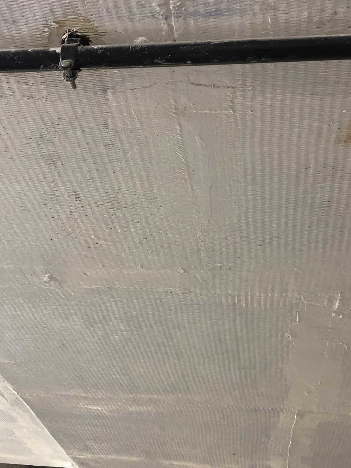 Painted ceiling with composite wrap texture and a black pipe.