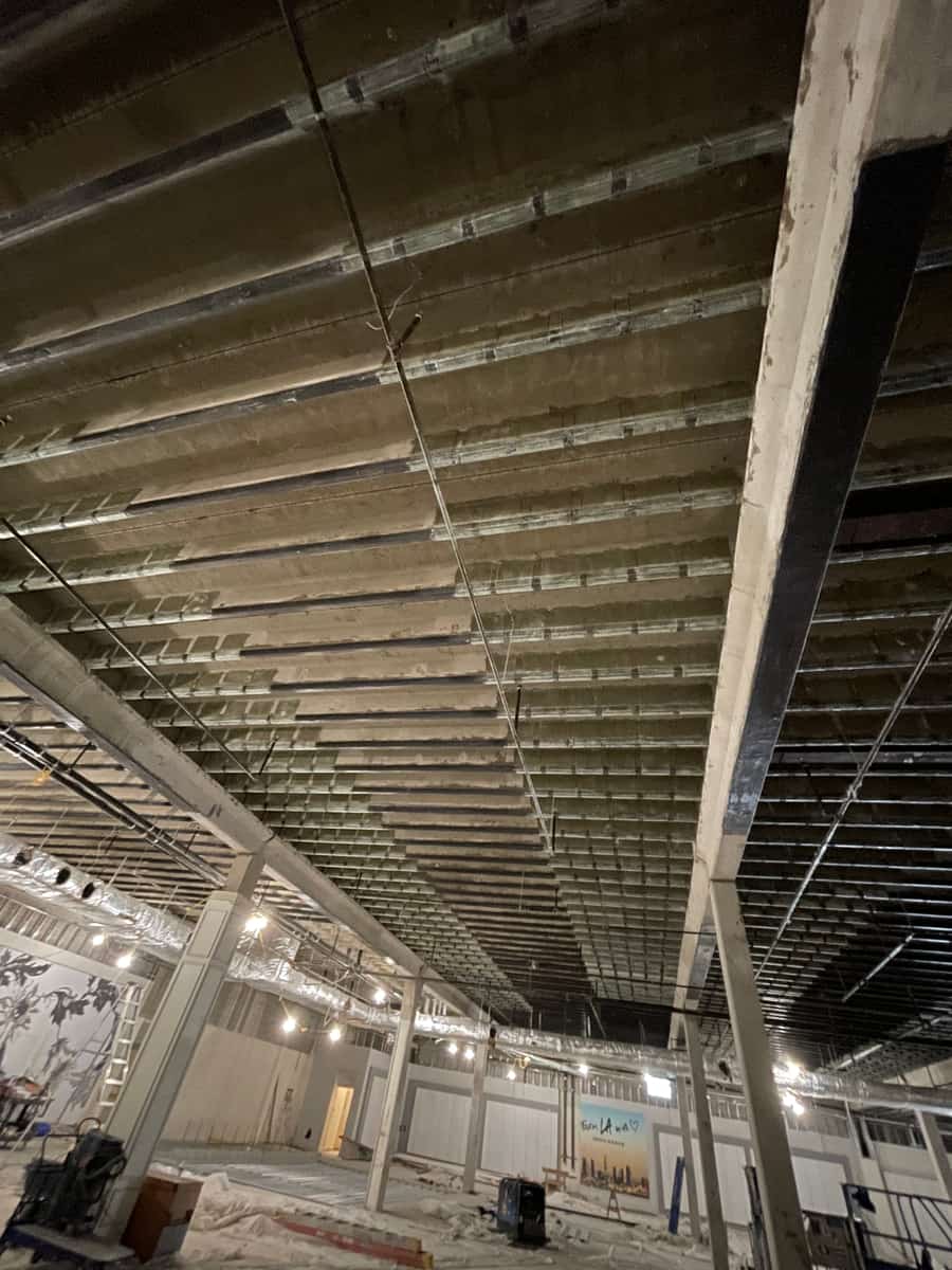 Pan-joist ceiling with carbon fiber bands over a large open floor under renovation.
