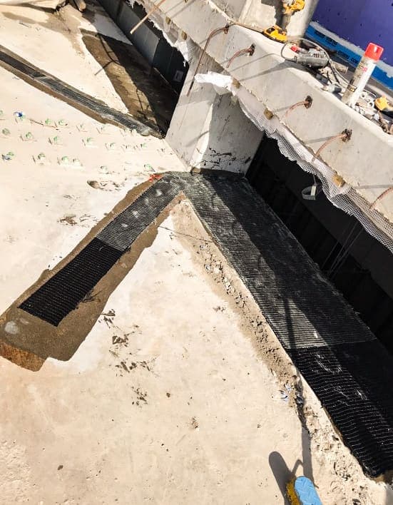 Trench cut in a slab top around a column stub with composite strips lining the channel.