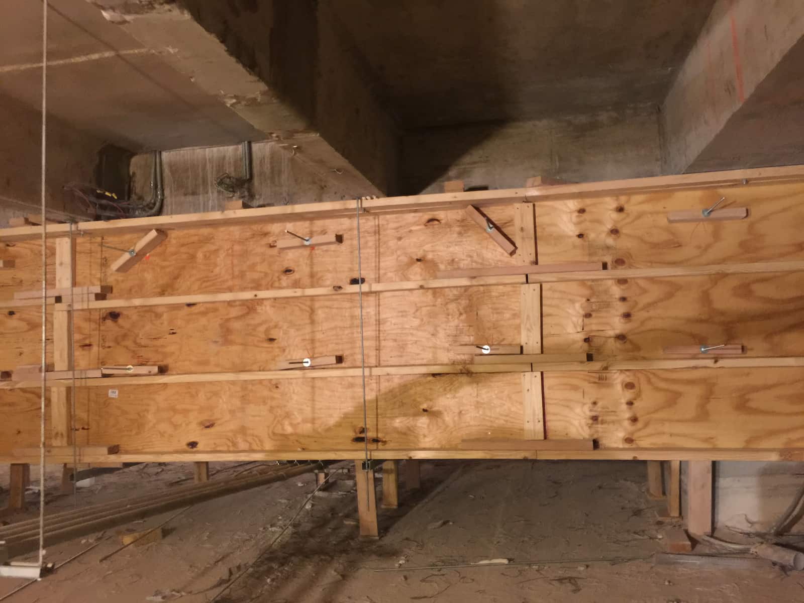 Plywood beam formwork with ties installed below existing concrete beams.