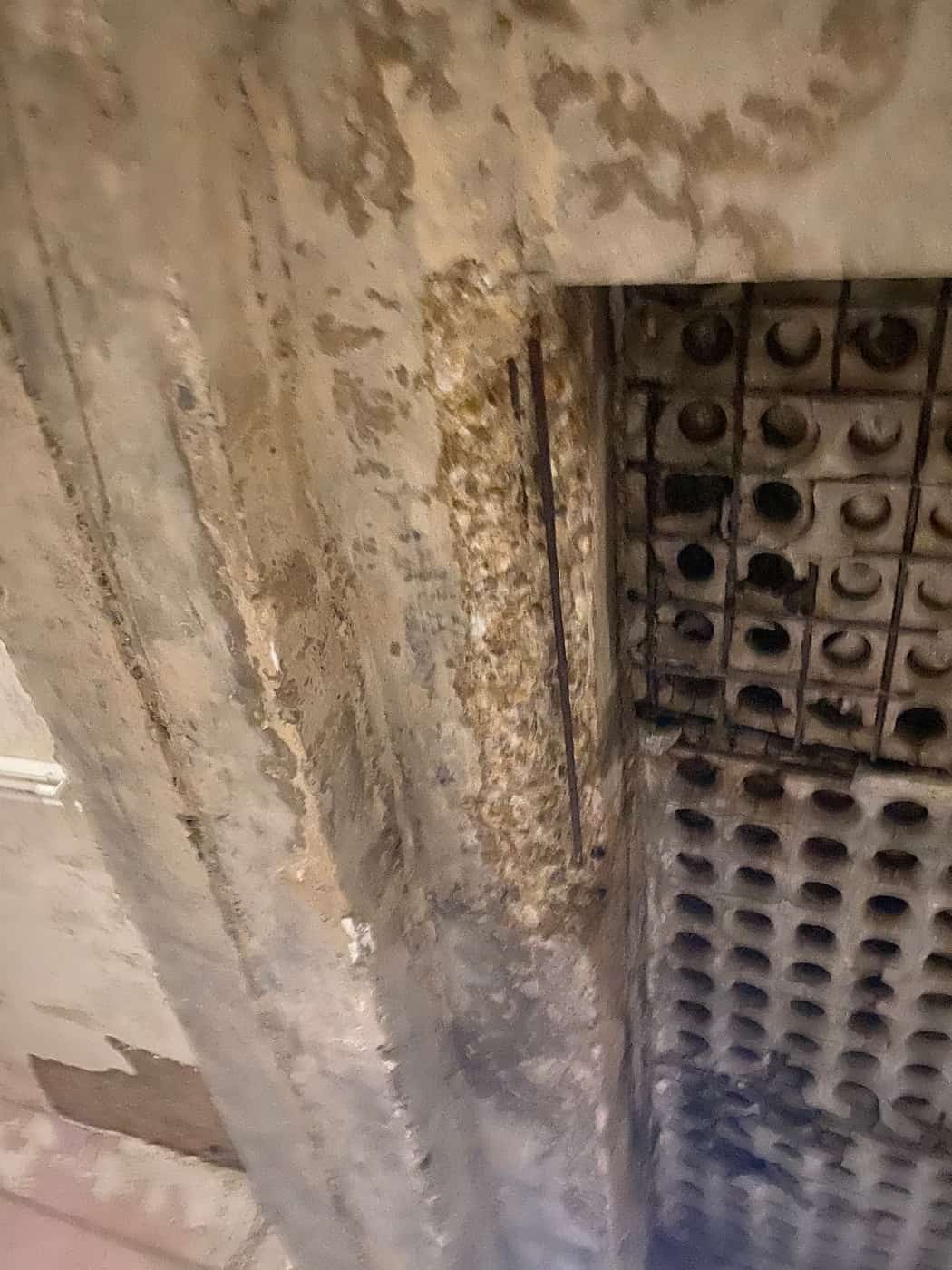 Spalled slab soffit exposing round void cells at a beam.
