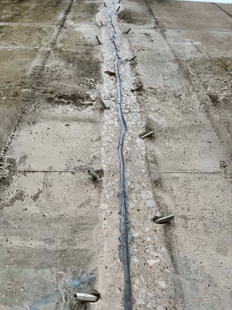 Vertical joint running along a concrete wall with metal pins.