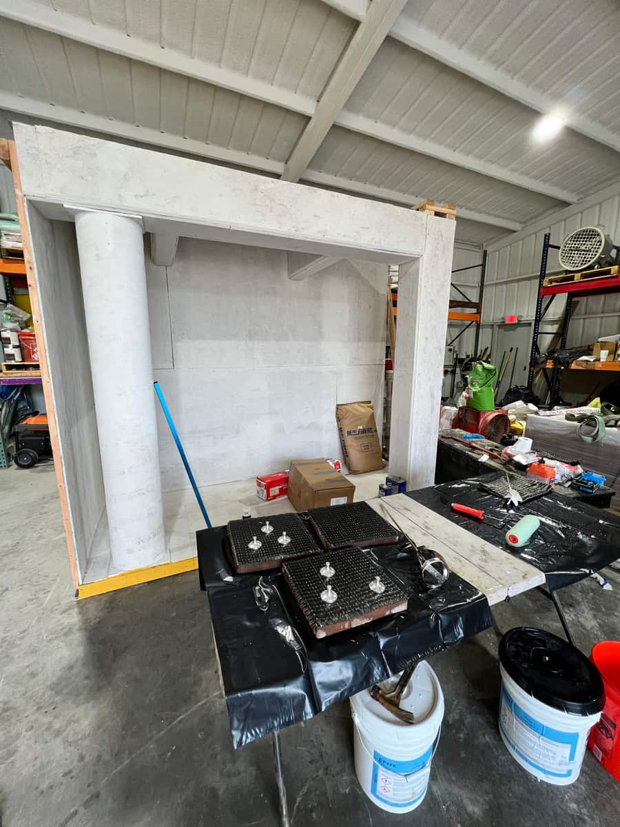 Mock-up concrete frame with a column in a warehouse with tools and buckets on a table.